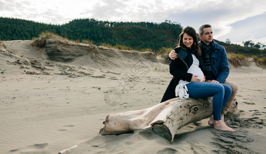 怀孕孕妇与她的伴侣海滩上背景图片