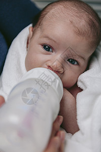 新生女婴在母亲和怀抱中喝着瓶子的奶粉图片