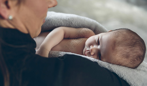 摇篮曲被母亲拥抱的毯子包着新生女婴背景