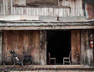 自行车停靠在老房的木墙上背景图片