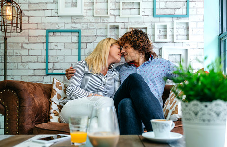夫妇在咖啡店的沙发上亲吻橙色高清图片素材