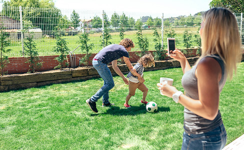 母亲拍摄她丈夫和儿子在花园玩耍的移动照片图片