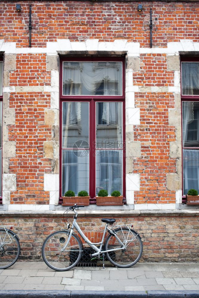 旧砖墙和窗户前的老旧自行车砖墙前的老自行车图片