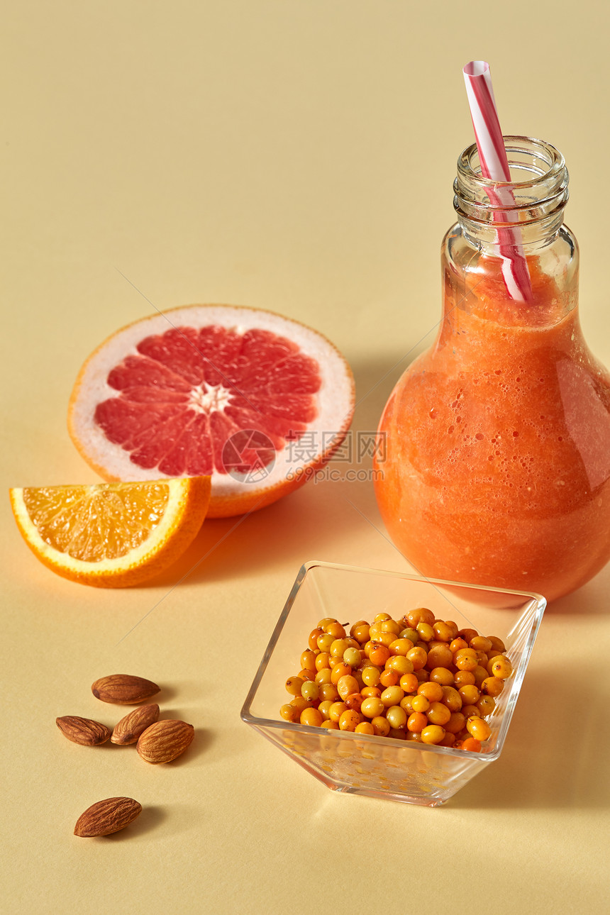 以橙色纸为背景的葡萄果橙色海角和杏仁在玻璃中的脱毒饮料健康品与海角杏仁橙色和葡萄果在玻璃中的维他命饮料橙色纸背景图片