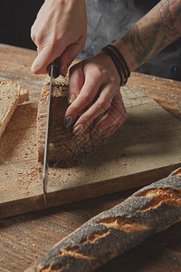 妇女手在木板上切新鲜面包手在切新鲜面包图片