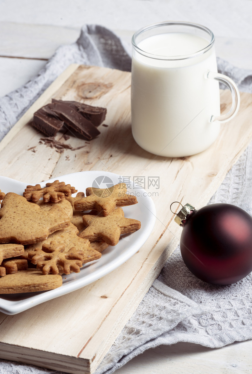 与传统的姜饼干关闭在盘子上和一杯牛奶在木板上厨房毛巾图片