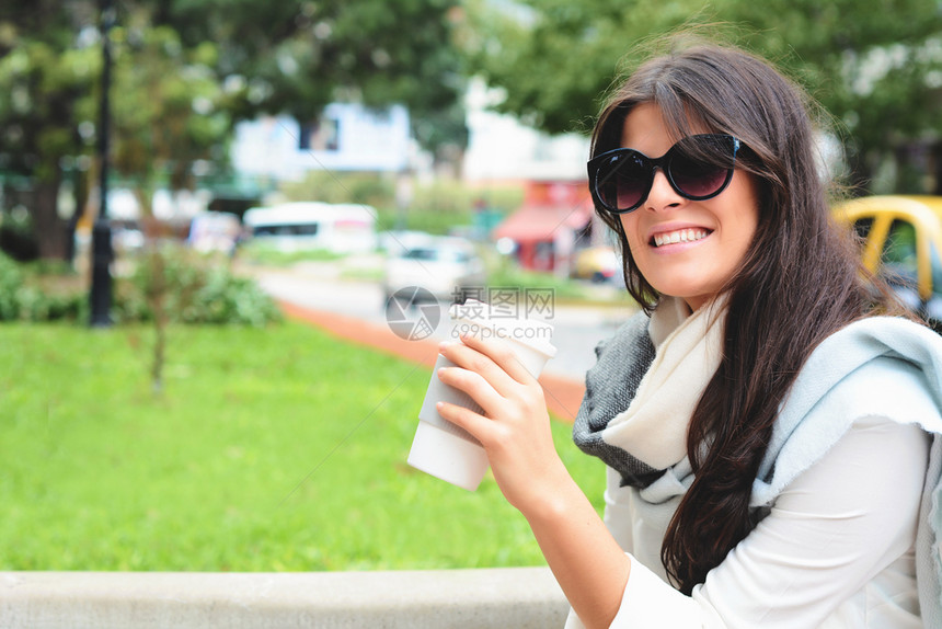 在街上拿着纸咖啡杯的美女肖像城市的风景户外图片