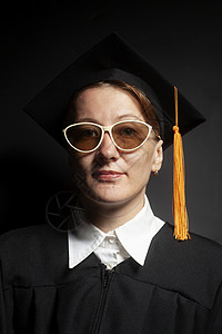 黑地皮和色背景毕业帽中的女单身汉肖像黑地皮和墨镜的毕业帽中女单身汉肖像背景图片