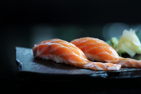 吃鱼黑色猫咪黑盘子上日本菜的三文鱼寿司背景