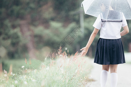 雨伞女孩下雨时在自然行走道上带着雨伞行走的亚裔女学生肖像背景