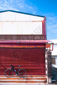 旧仓库红色锈墙对面停车的自行图片