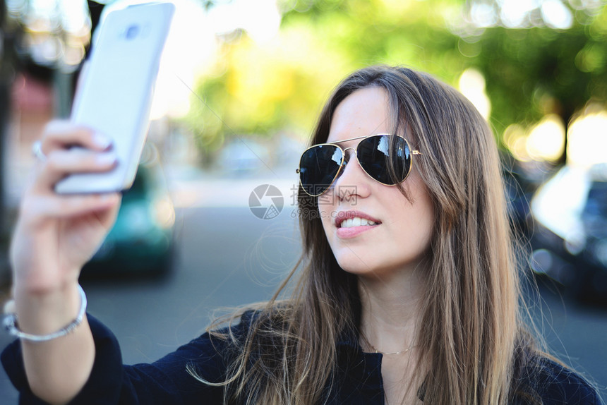 美女用手机在户外自拍图片