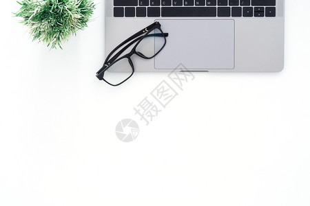 书桌上的眼镜与笔记本电脑背景图片