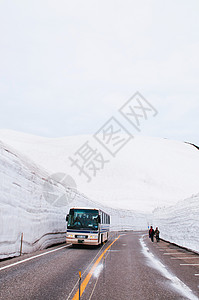 日本雅潘的公交行驶于雪墙之间道路视图背景图片