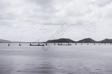 夏季和平的Songkhla湾海景渔民在船上用长的棍钓鱼图片