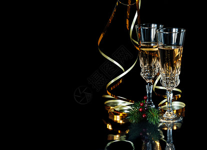 黑色背景上的节日组成两杯玻璃晶香槟金蛇绿树枝和红荷利果并带有复制空间背景图片
