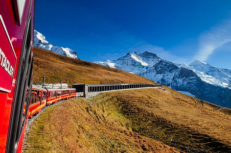 山君不离2013年9月4日卢特布罗宁瑞士红色的君frau铁路列车在克莱因scheidg站攀登到丘特弗劳乔赫通过草场和艾格尔蒙奇山峰背景