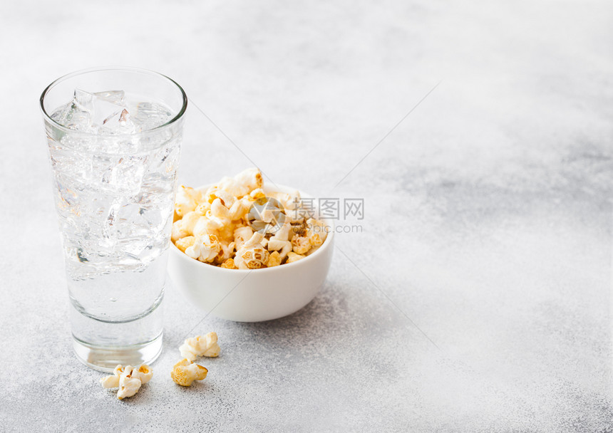 一杯柠檬汁苏打饮料冰块和白碗爆米花零食在石器厨房背景图片