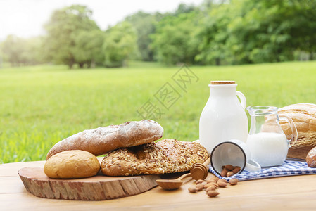 绿色花园背景模糊的木桌上面包和牛奶图片
