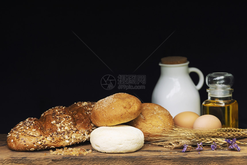 黑色背景的木桌上面包牛奶和油图片