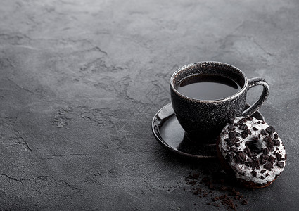 黑咖啡杯有碟子和甜圈黑石餐桌背景上有黑饼干文本空间背景图片