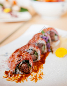 瓷砖板上鲜美的日本黄瓜牛肉寿司卷和酱汁近镜头图片