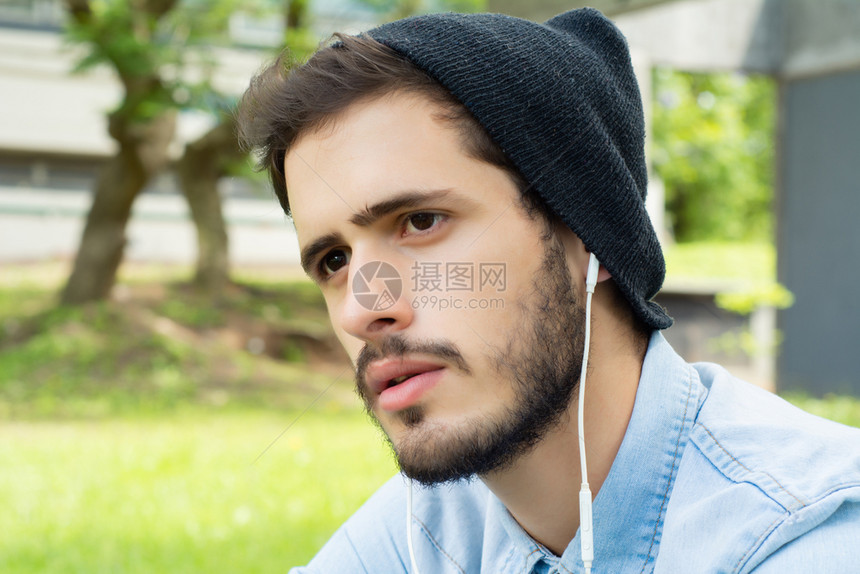 年轻人在阳光明媚的一天用耳机收听音乐的肖像图片