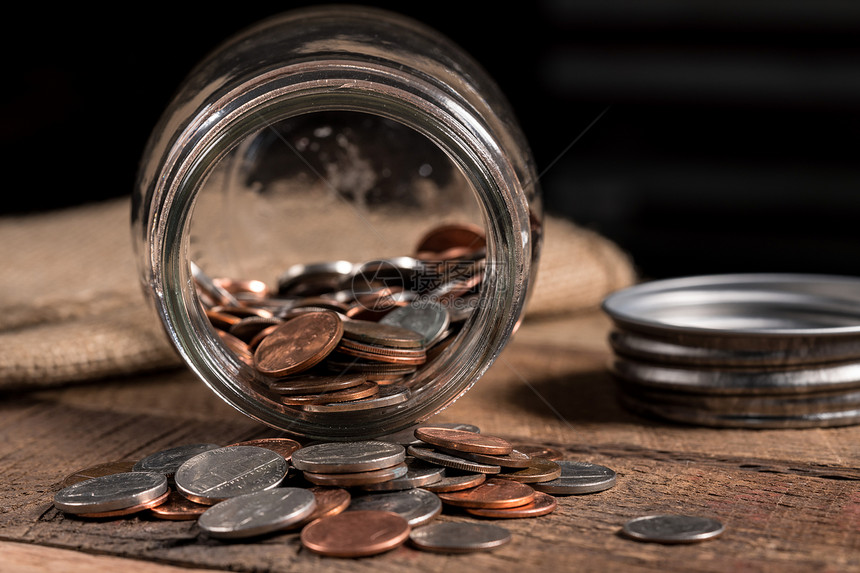 在木制桌上的玻璃储蓄罐中留下几个小硬币的贫穷概念形象玻璃砖罐里面有几枚硬币用来说明贫穷图片