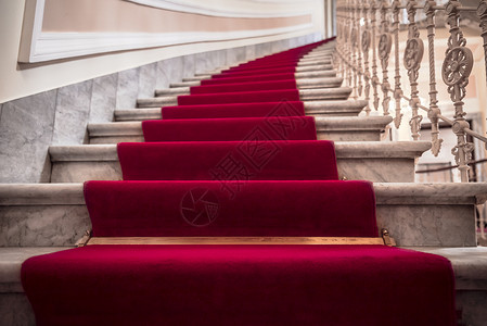 室内豪华建筑大理石楼梯上面盖着红地毯背景图片