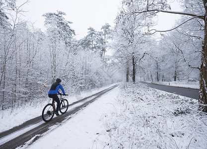 冬季骑着山车的男子经过雪中森林图片