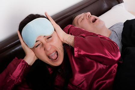 男人在床上打呼噜时用手堵住耳朵高清图片