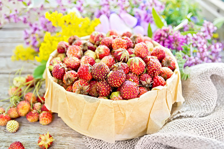 野生成熟的草莓在木板背景上装有羊皮卷毛和野花的树皮箱中背景图片