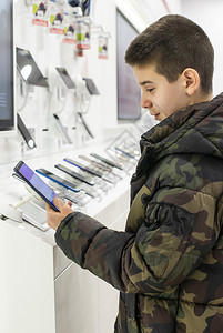 商店货架上的智能手机通讯和技术概念男孩在技术商店购买手机图片