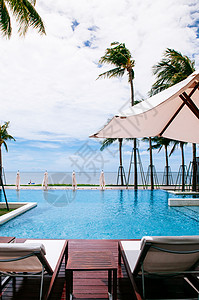 2014年6月日2014年华欣泰国热带海边度假胜地风格的无穷热带海边度假胜地缘泳池夏天在白色雨伞和椰子树下有海滩床和背景图片
