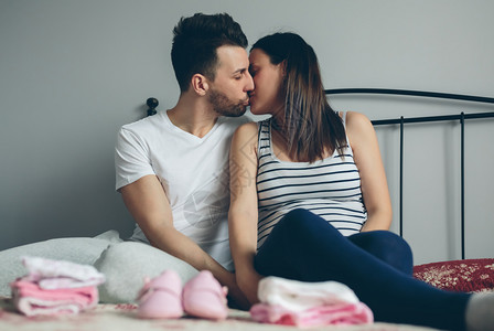 男子在卧室中亲吻怀孕的妻子图片
