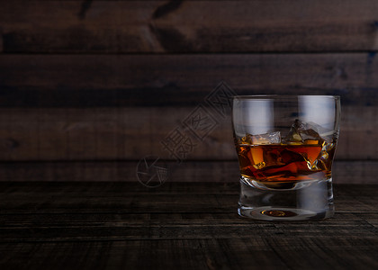 玻璃威士忌和木制桌底的冰块图片