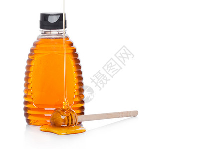 含有机天然蜂蜜的塑料罐瓶装有机天然蜂蜜白底带棍子和液体蜂蜜图片