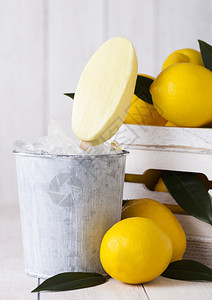 软糯冰棍用柠檬冷冻果汁雪糕制成的冰淇淋放在死桶里和一箱生柠檬背景