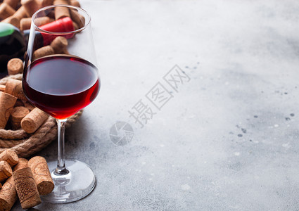 优雅的玻璃和一瓶红葡萄酒里面装着一盒软木和开瓶器放在厨房桌底图片