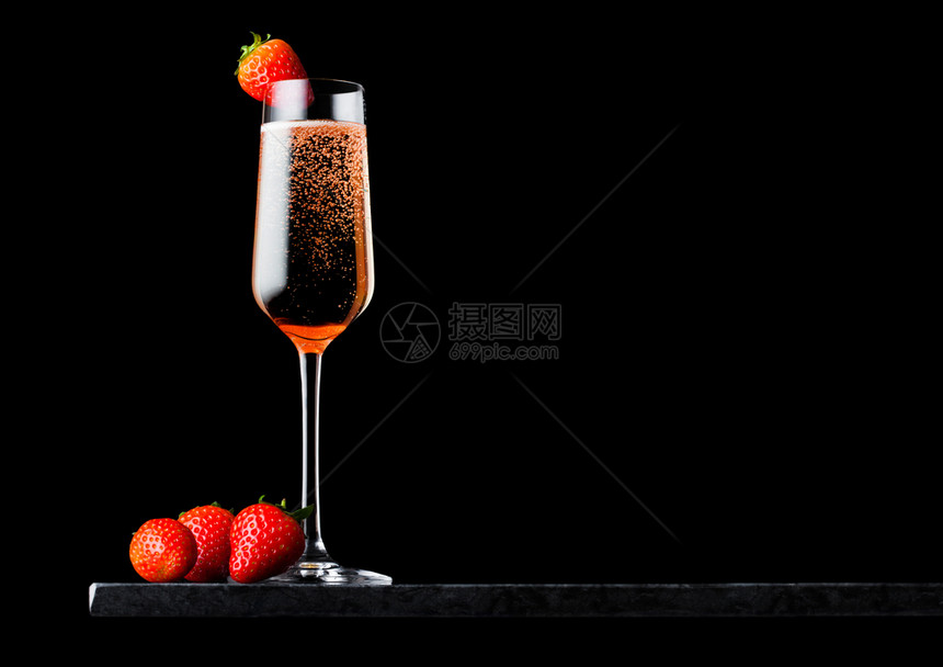 优雅的粉红玫瑰香槟上面有草莓在黑色大理石板上在黑色背景图片