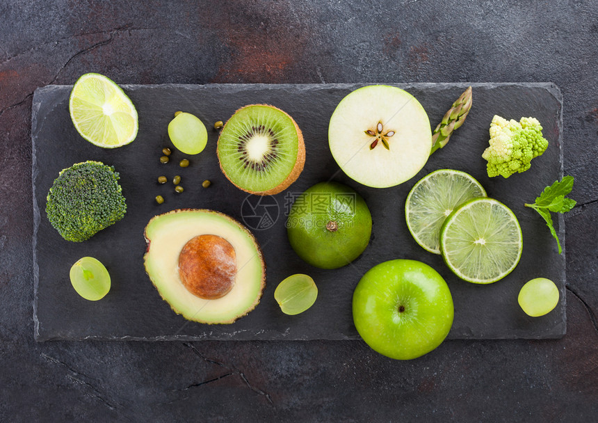石板背景的新鲜有机生绿色种子水果和蔬菜鳄梨石灰苹果奎威和葡萄以及花椰菜和图片