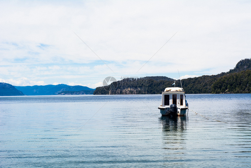 在自然环境中平静湖水上航行的渔船图片