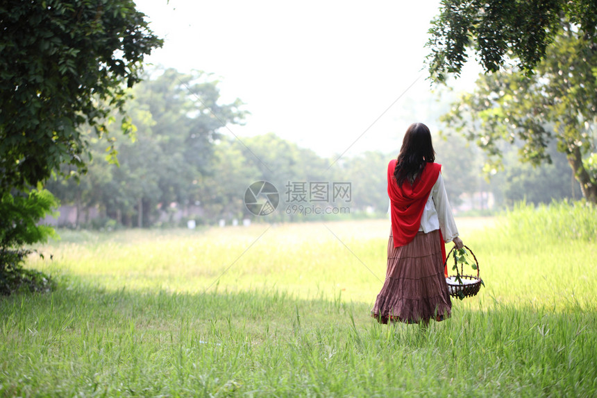 女孩提着花篮在草丛的背影图片