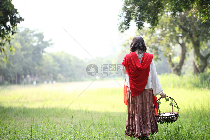 女孩提着花篮在草丛的背影图片