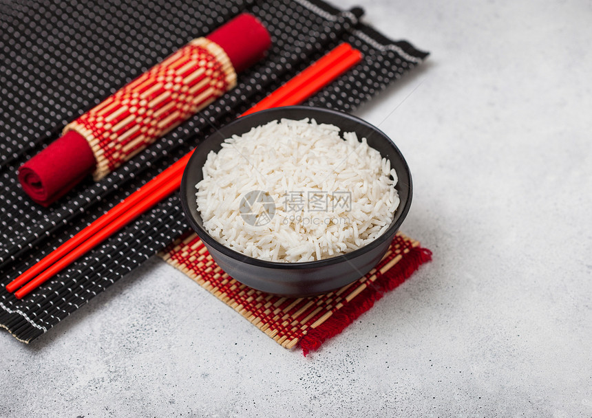 黑碗加煮有机巴斯马提茉莉米饭竹地垫上有红筷子浅的厨房桌底有红皮巾图片