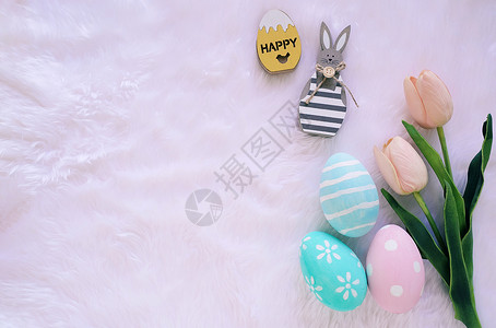 白毛背景粉色郁金香和带涂鸦的鸡蛋背景图片