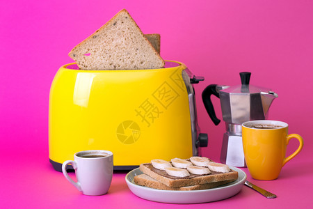 黄面包机和一杯粉红背景的咖啡高清图片