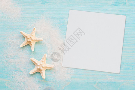 两个海星和白沙处于蓝色淡木甲板的背景背景图片