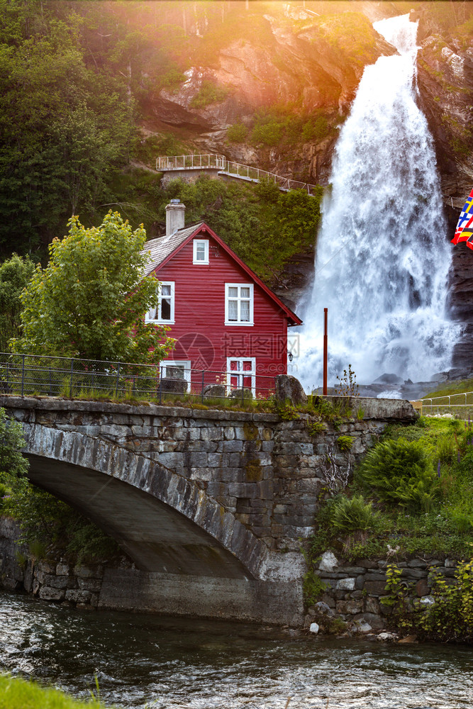 传统挪威红木屋和背景中的斯坦达尔福森瀑布图片