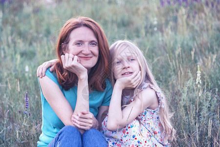 母亲和女儿坐在草地上看着镜头图片